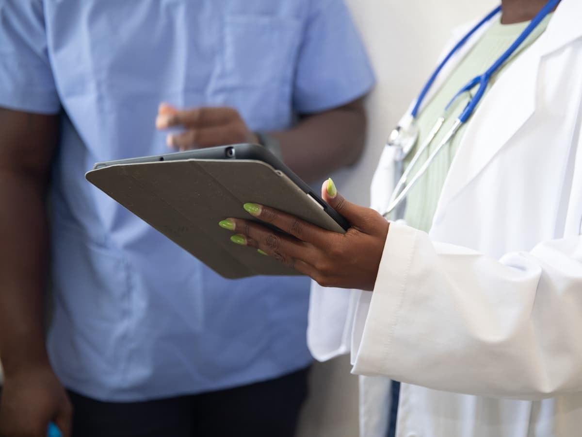 Personnel soignant consultant une tablette dans un couloir